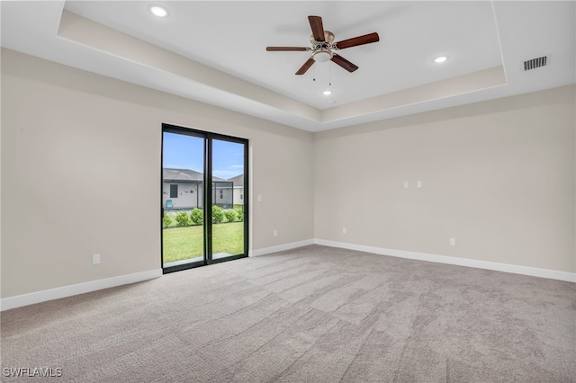 unfurnished room featuring ceiling fan, a raised ceiling, and carpet floors