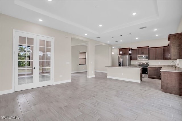 kitchen featuring stainless steel appliances, french doors, sink, a tray ceiling, and a center island