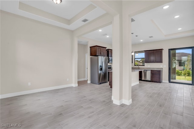 unfurnished living room featuring a raised ceiling and light hardwood / wood-style flooring