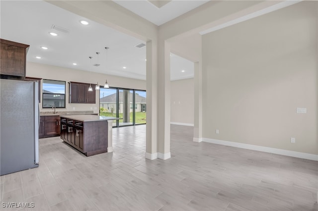 kitchen featuring decorative light fixtures, dark brown cabinetry, sink, a center island, and white fridge