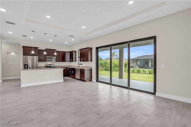 kitchen featuring a tray ceiling, stainless steel appliances, a kitchen island, and dark brown cabinetry