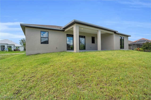 back of property featuring a lanai and a lawn