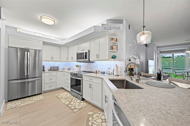 kitchen featuring light hardwood / wood-style flooring, backsplash, white cabinets, sink, and stainless steel appliances