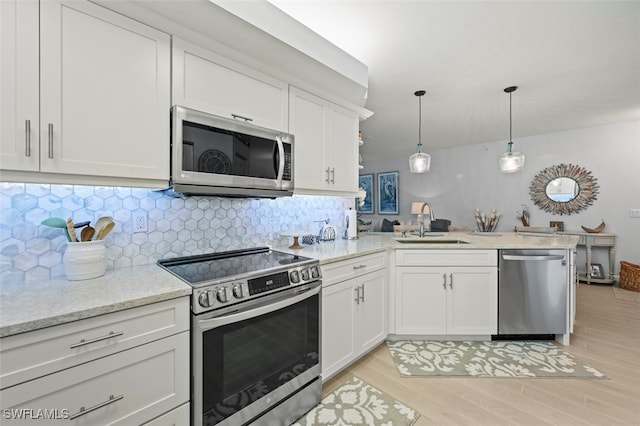 kitchen with backsplash, stainless steel appliances, light hardwood / wood-style floors, white cabinetry, and kitchen peninsula