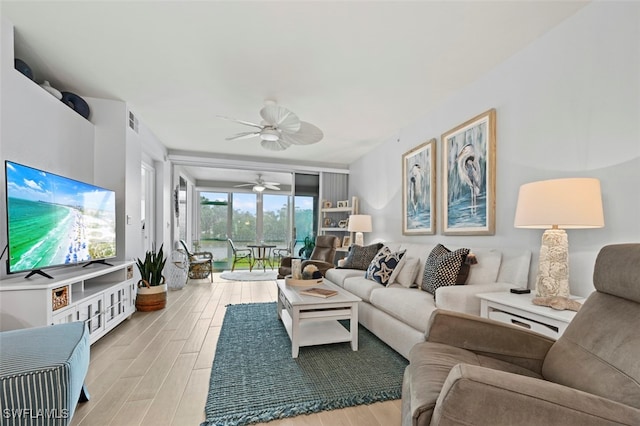 living room with ceiling fan, light wood-type flooring, and a wall of windows