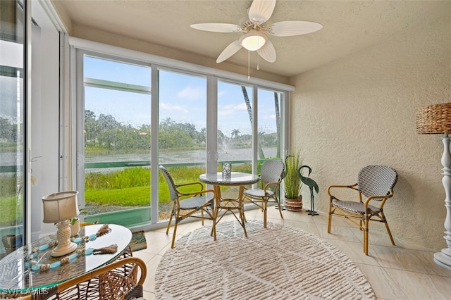 sunroom / solarium with ceiling fan and a water view