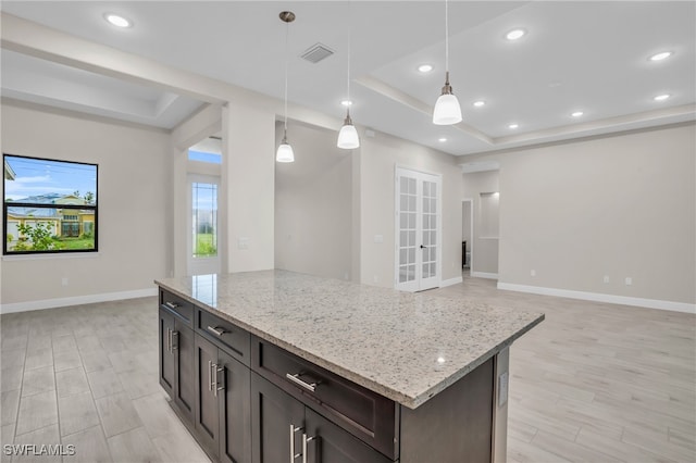 kitchen featuring light hardwood / wood-style floors, decorative light fixtures, and a tray ceiling