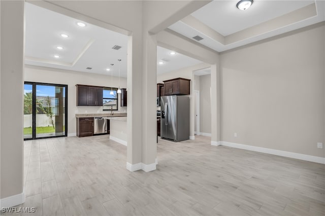 unfurnished living room with light hardwood / wood-style floors, a raised ceiling, and sink