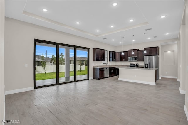 kitchen with appliances with stainless steel finishes, a center island, dark brown cabinetry, and a raised ceiling