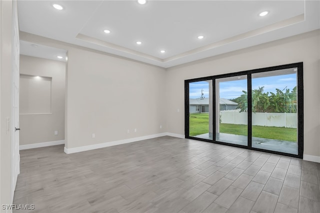 empty room featuring light hardwood / wood-style flooring and a tray ceiling