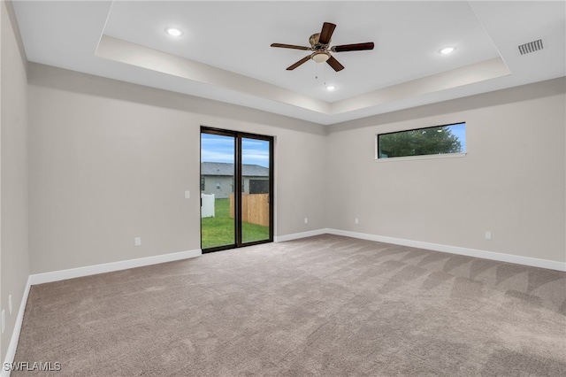 unfurnished room with ceiling fan, a raised ceiling, and carpet