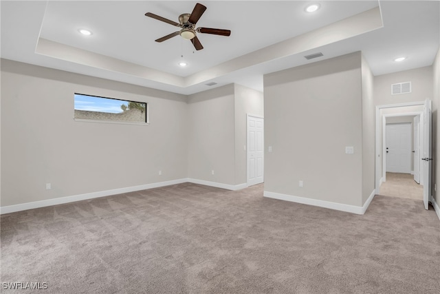 spare room featuring ceiling fan, a raised ceiling, and light colored carpet