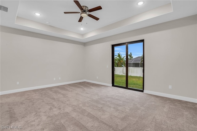 carpeted spare room featuring ceiling fan and a raised ceiling