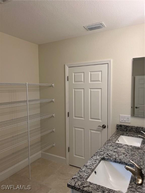 bathroom featuring tile patterned flooring, a textured ceiling, and vanity