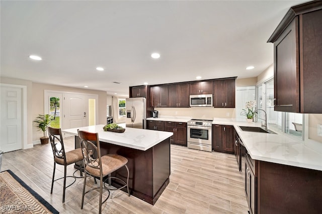 kitchen featuring sink, stainless steel appliances, a kitchen island, and a healthy amount of sunlight