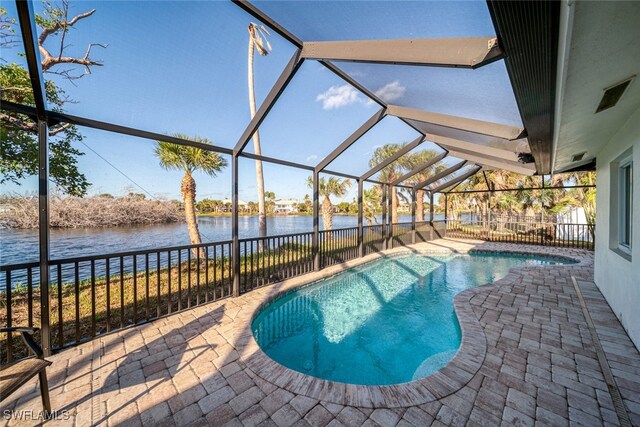 view of swimming pool featuring glass enclosure, a patio area, and a water view