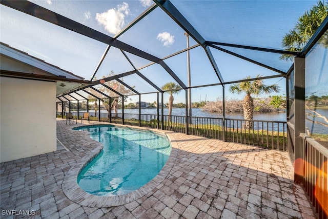 view of swimming pool featuring a water view, a patio area, and a lanai