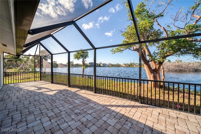 view of patio featuring glass enclosure and a water view