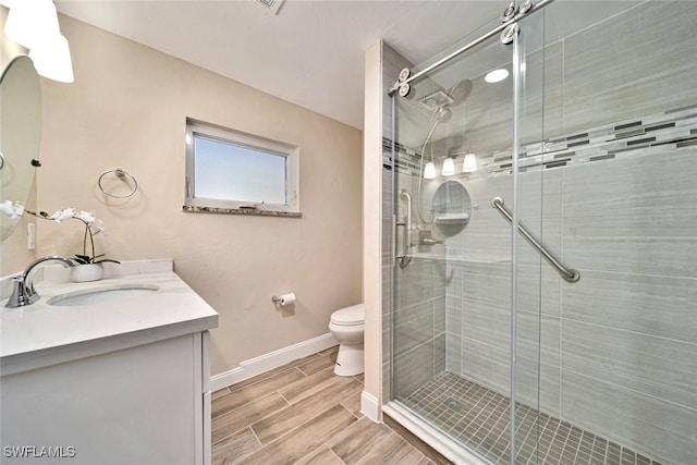 bathroom with a shower with shower door, vanity, and toilet