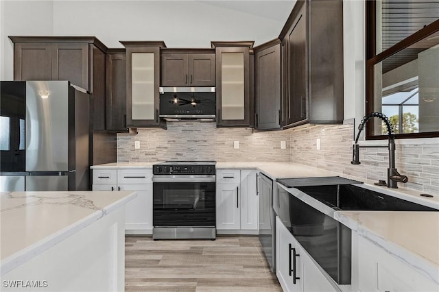 kitchen with lofted ceiling, sink, stainless steel appliances, decorative backsplash, and white cabinets