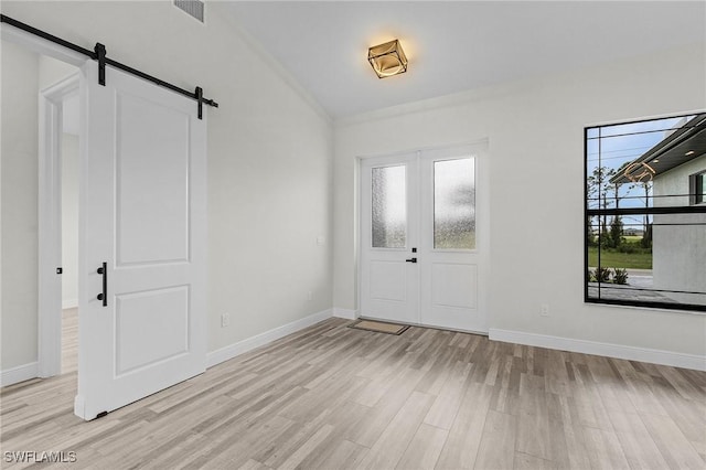 entrance foyer featuring french doors, a barn door, and light wood-type flooring