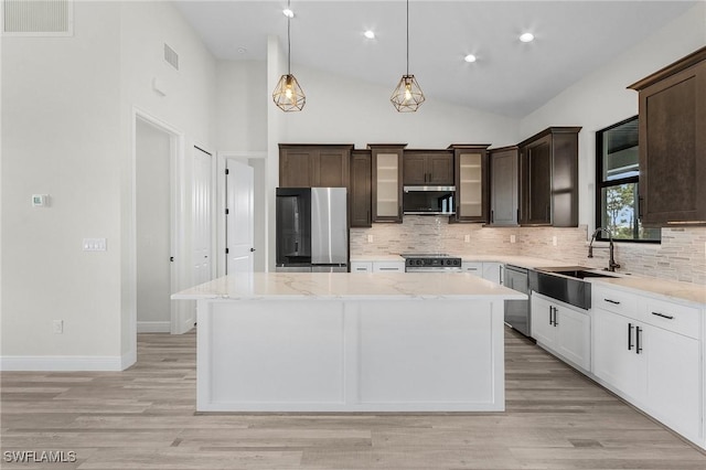 kitchen featuring dark brown cabinetry, sink, a center island, appliances with stainless steel finishes, and white cabinets