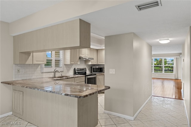 kitchen featuring light stone counters, stainless steel appliances, visible vents, a peninsula, and under cabinet range hood