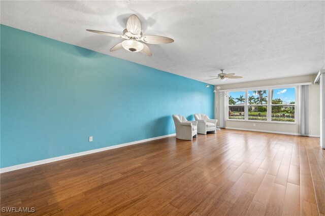 unfurnished room with a ceiling fan, a textured ceiling, baseboards, and wood finished floors