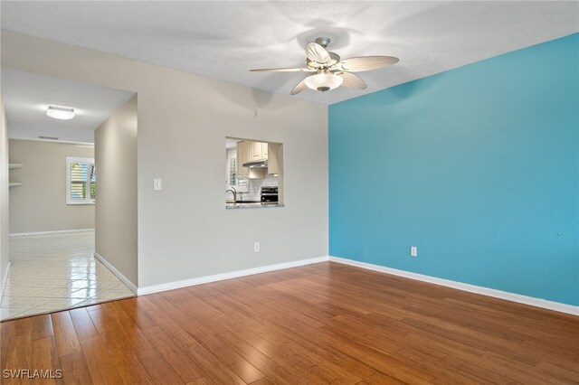 spare room with sink, ceiling fan, light tile patterned flooring, and a textured ceiling