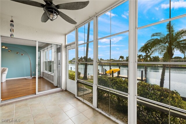 unfurnished sunroom with ceiling fan and a water view