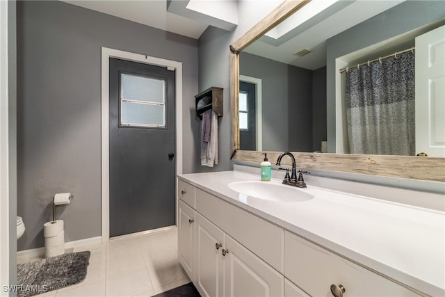 bathroom with vanity, toilet, a skylight, and tile patterned flooring