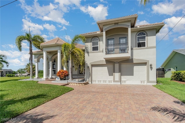 mediterranean / spanish house featuring a garage, a front lawn, and a balcony