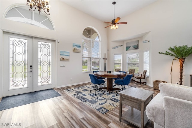 entryway with hardwood / wood-style floors, ceiling fan with notable chandelier, high vaulted ceiling, and french doors