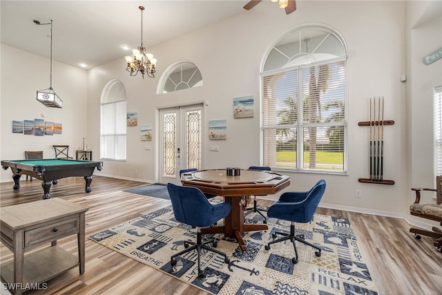 game room with billiards, high vaulted ceiling, ceiling fan with notable chandelier, french doors, and light hardwood / wood-style floors