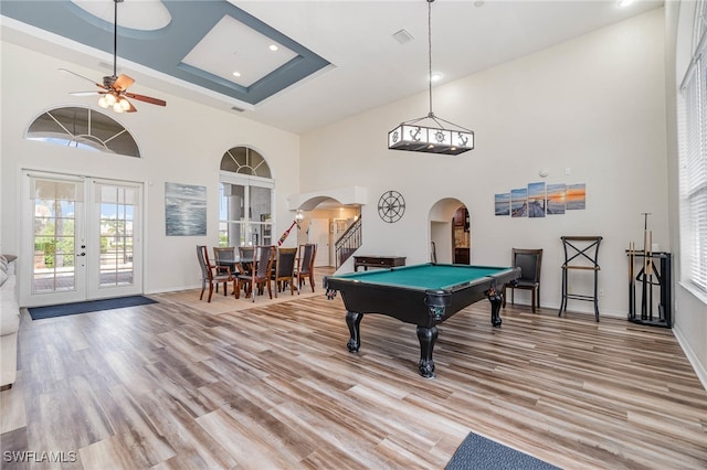 rec room featuring ceiling fan, billiards, light wood-type flooring, a towering ceiling, and french doors