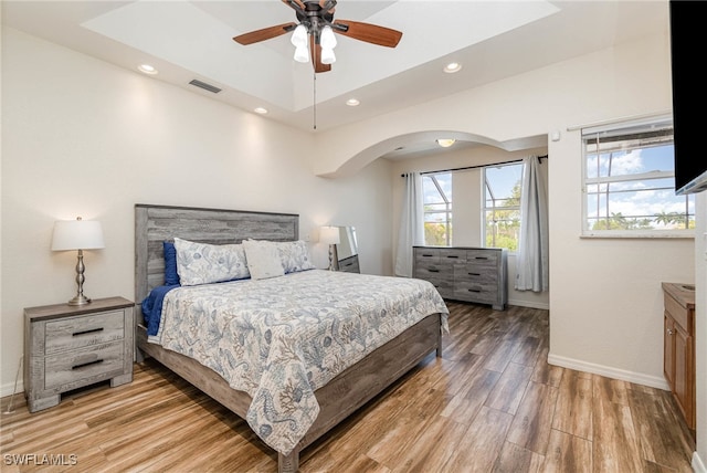 bedroom featuring ceiling fan, a raised ceiling, and hardwood / wood-style floors