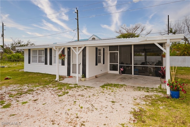 rear view of house featuring a patio, a sunroom, and a lawn