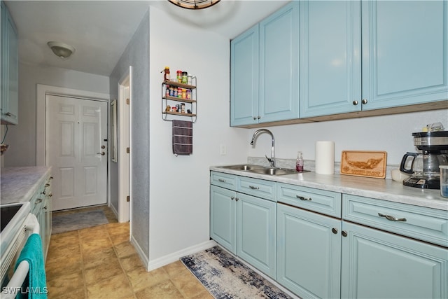 kitchen featuring sink, stove, light tile patterned flooring, and blue cabinetry