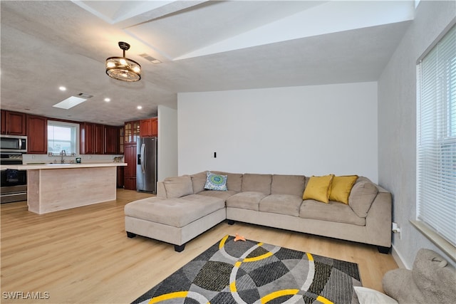 living room with sink, light hardwood / wood-style floors, and vaulted ceiling