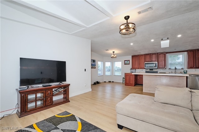 living room with sink, vaulted ceiling, and light hardwood / wood-style floors