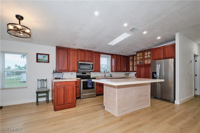 kitchen featuring sink, light hardwood / wood-style flooring, appliances with stainless steel finishes, and a kitchen island