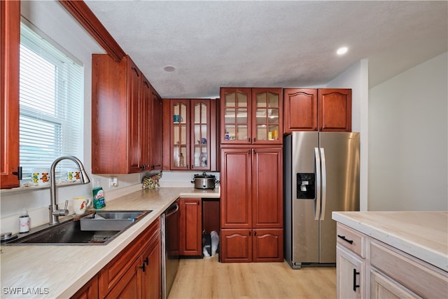 kitchen featuring sink, stainless steel appliances, light hardwood / wood-style flooring, and a textured ceiling