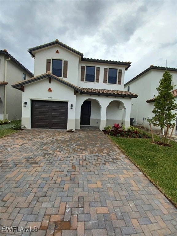 mediterranean / spanish home with central AC unit and a garage