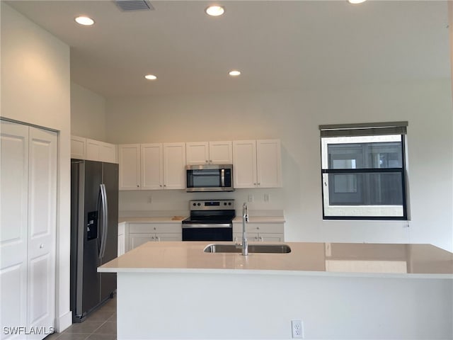 kitchen with sink, stainless steel appliances, white cabinets, and light tile patterned floors