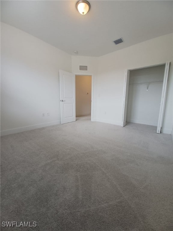 unfurnished bedroom with a closet and light colored carpet