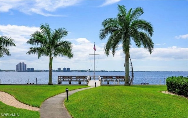 surrounding community featuring a dock, a lawn, and a water view