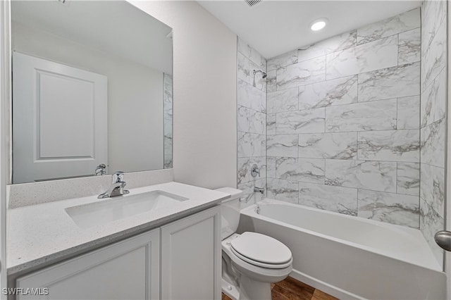 full bathroom featuring hardwood / wood-style floors, tiled shower / bath, toilet, and vanity