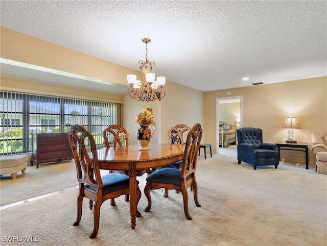 dining room with a textured ceiling, an inviting chandelier, and light carpet