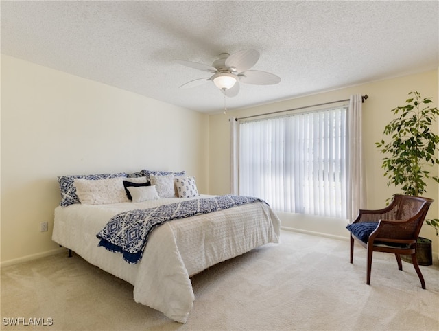 carpeted bedroom featuring ceiling fan and a textured ceiling