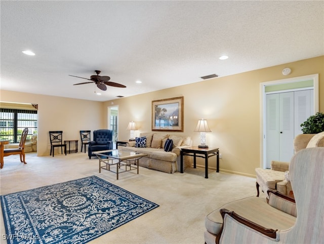 carpeted living room with a textured ceiling and ceiling fan